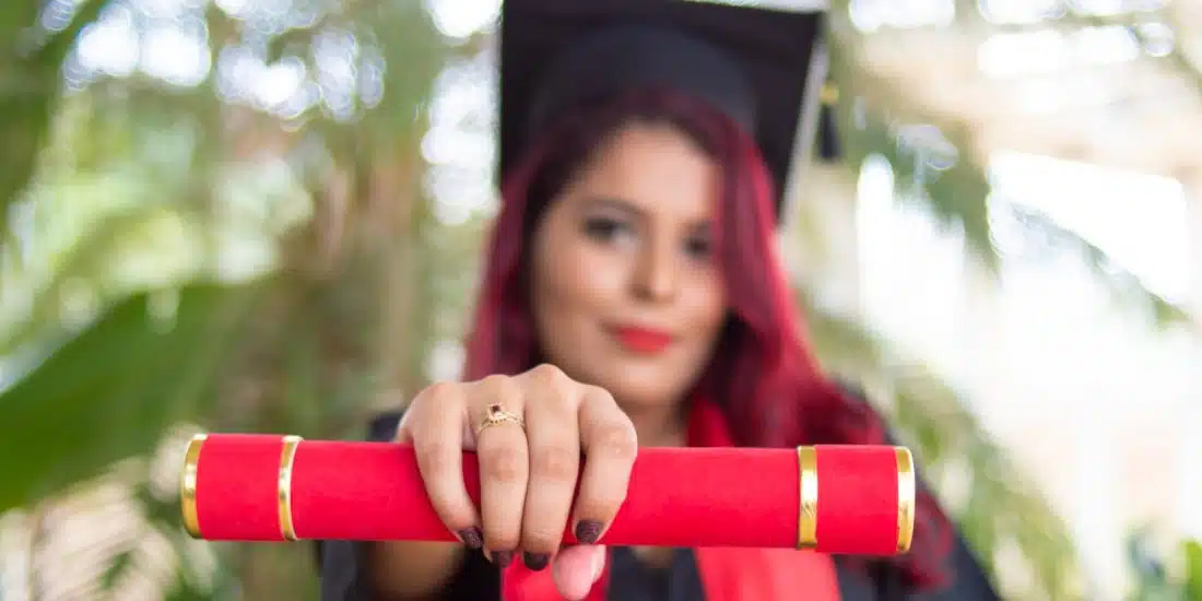 woman in red long sleeve shirt holding red and black academic hat