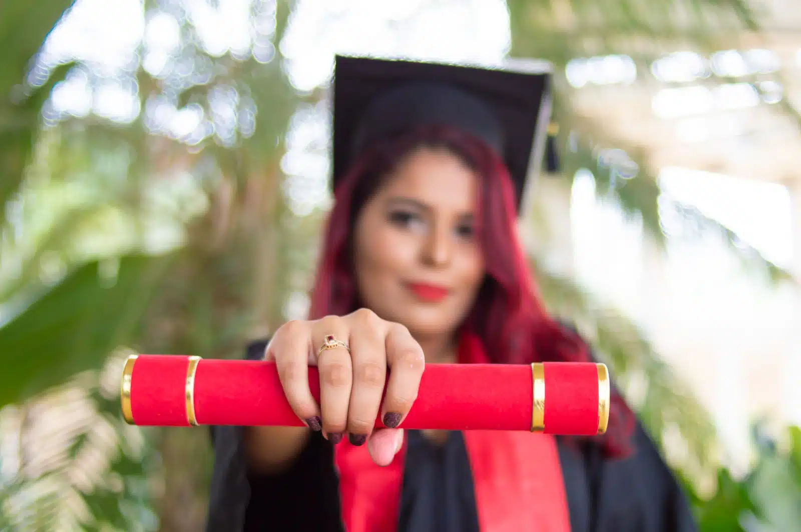 woman in red long sleeve shirt holding red and black academic hat