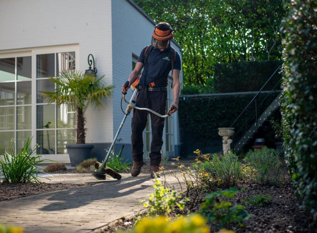 man in black t-shirt and blue denim jeans holding shovel