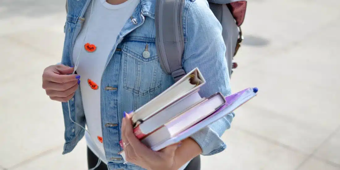 woman wearing blue denim jacket holding book