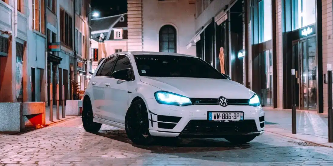 a white car parked on a brick road between buildings